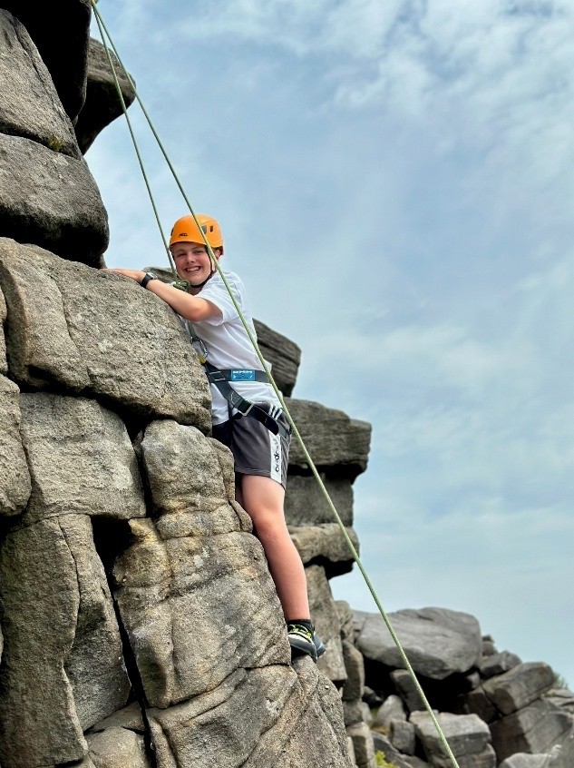 Student climbing a rock face on the Longshaw Estate