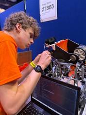 Gil tinkering with a robot as part of his robotics team, High Peak Robotics