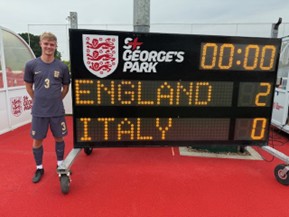Trainee teacher at St George's Park standing next to a score board which reads England 2, Italy 0