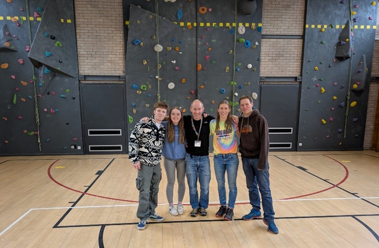 Staff and volunteers smiling in front of climbing walls