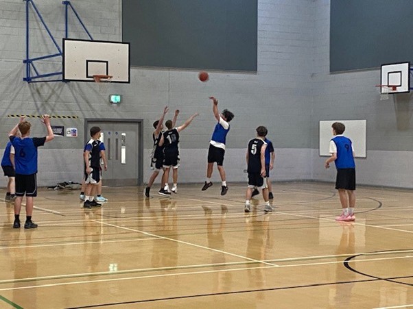 Key Stage 4 boys playing basketball on a basketball court
